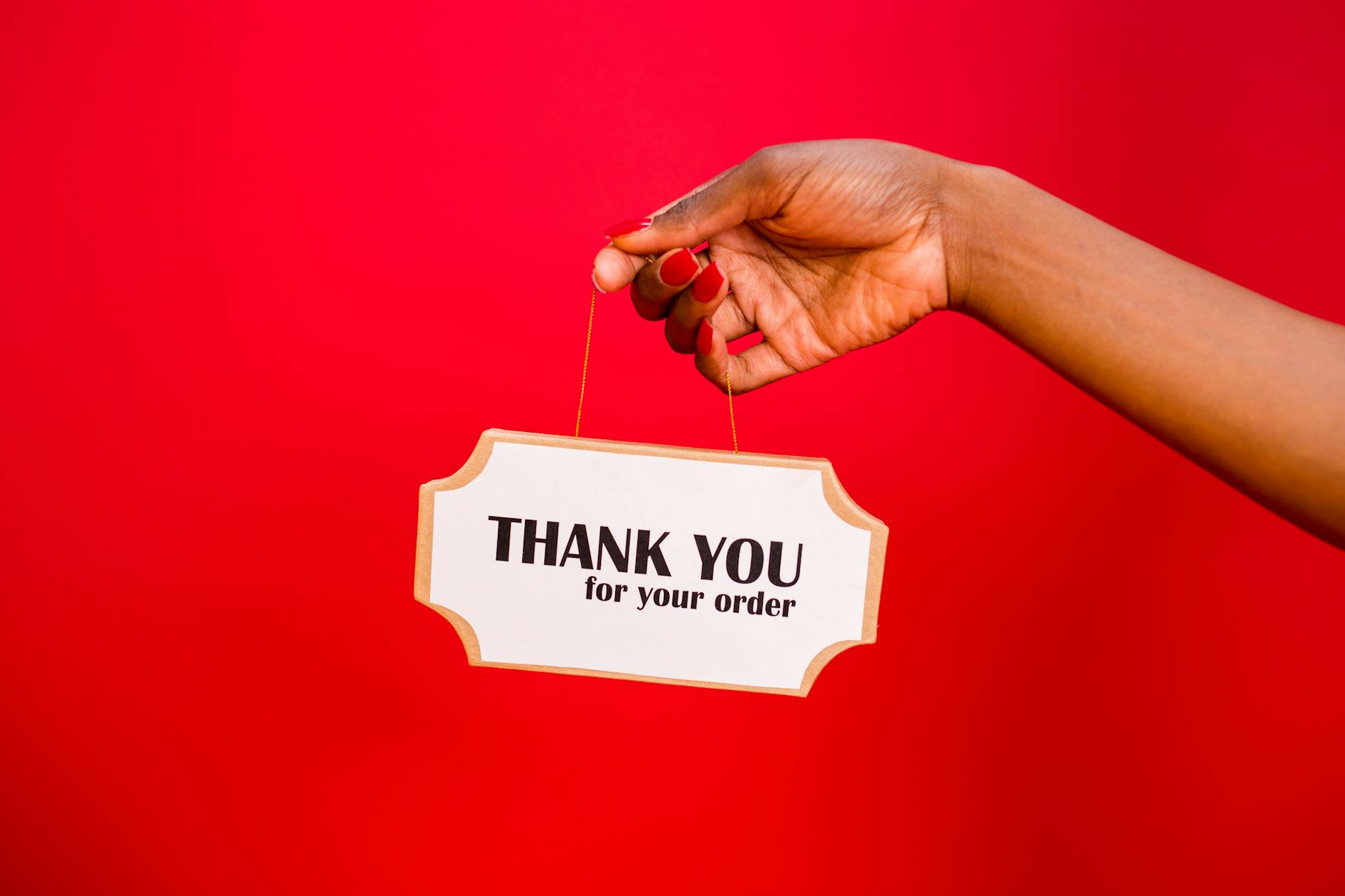 A person holding a thank you sign against a vibrant red background.