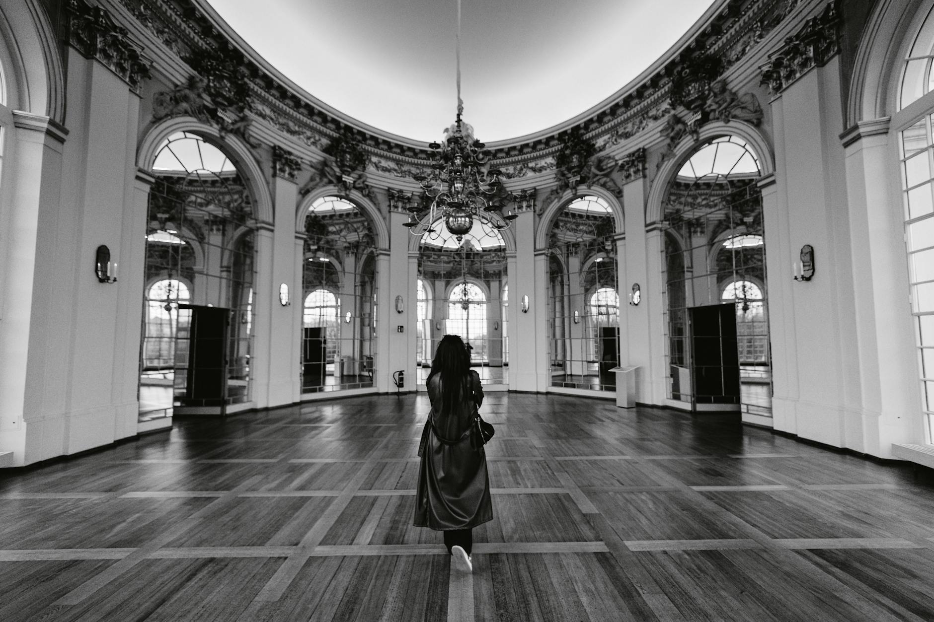 Black and white photo of a woman in an ornate ballroom in Berlin. Elegant and timeless.
